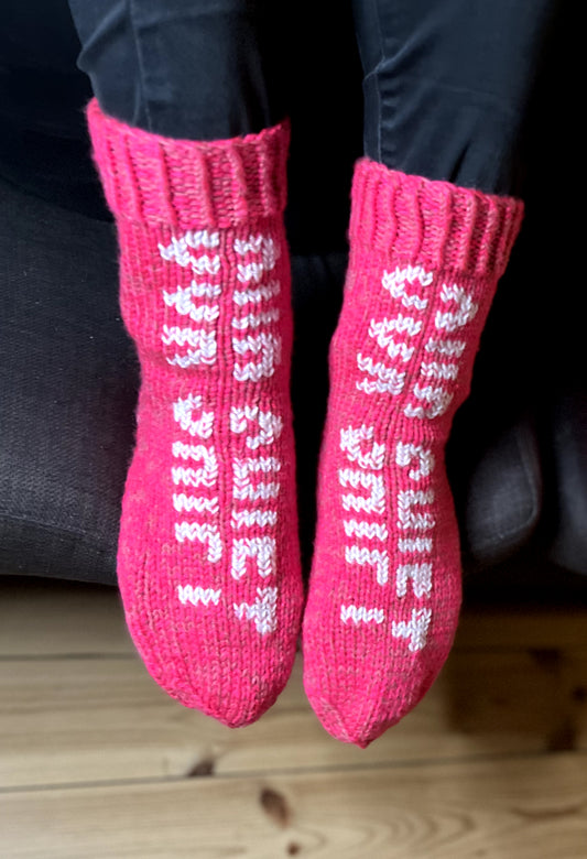 Pink hand-knitted socks by Grandmas and Grandpas with OUR SHIFT logo. 